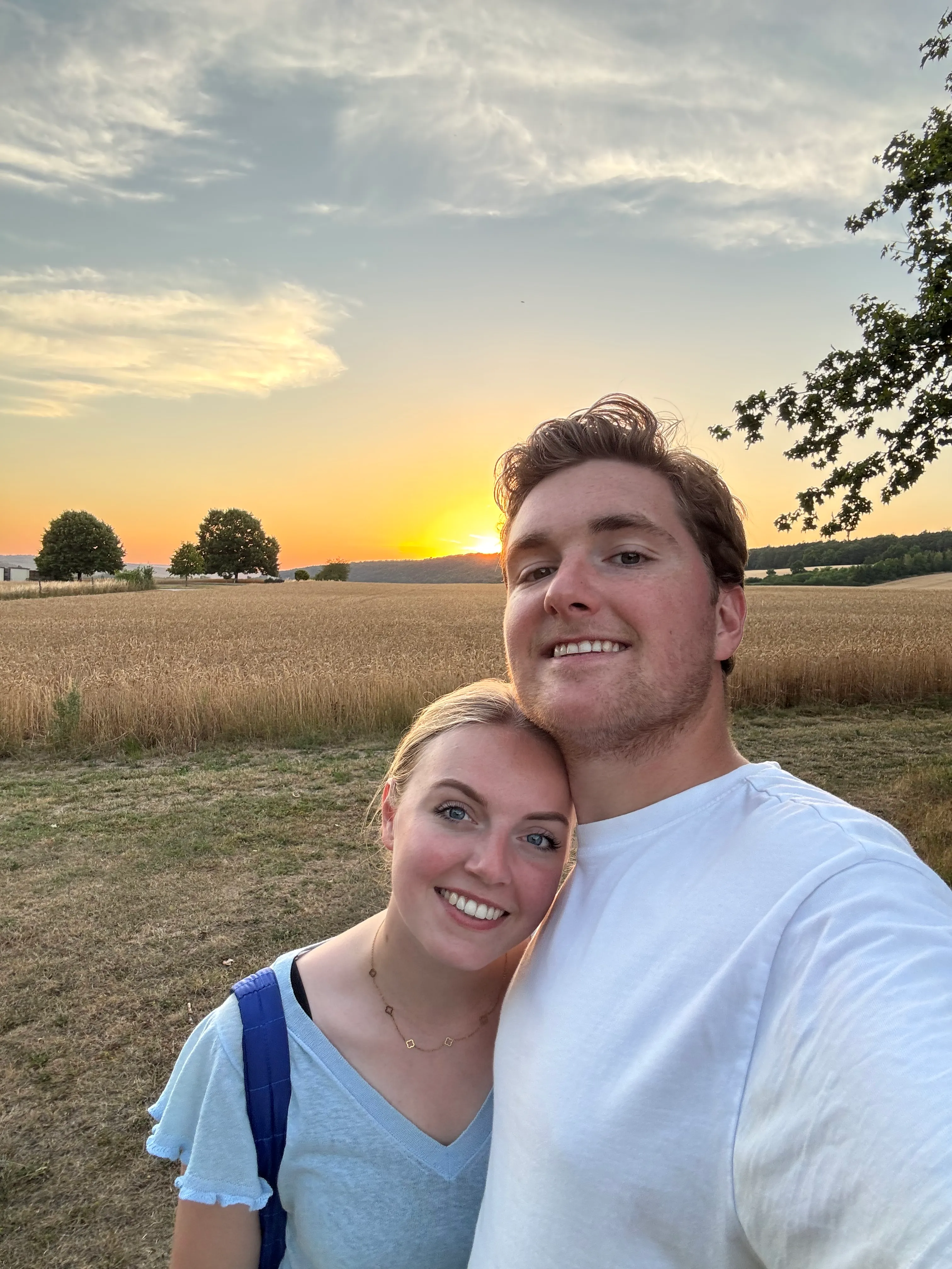 Selfie van Fleur en Laurens in een veld bij zonsondergang